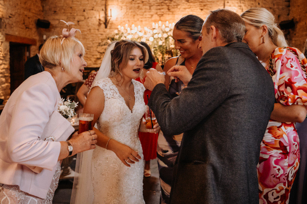 cripps barn wedding magic bride and her family are show a magic trick by Brett at a barn wedding venue, Cripps Barn near Tetbury